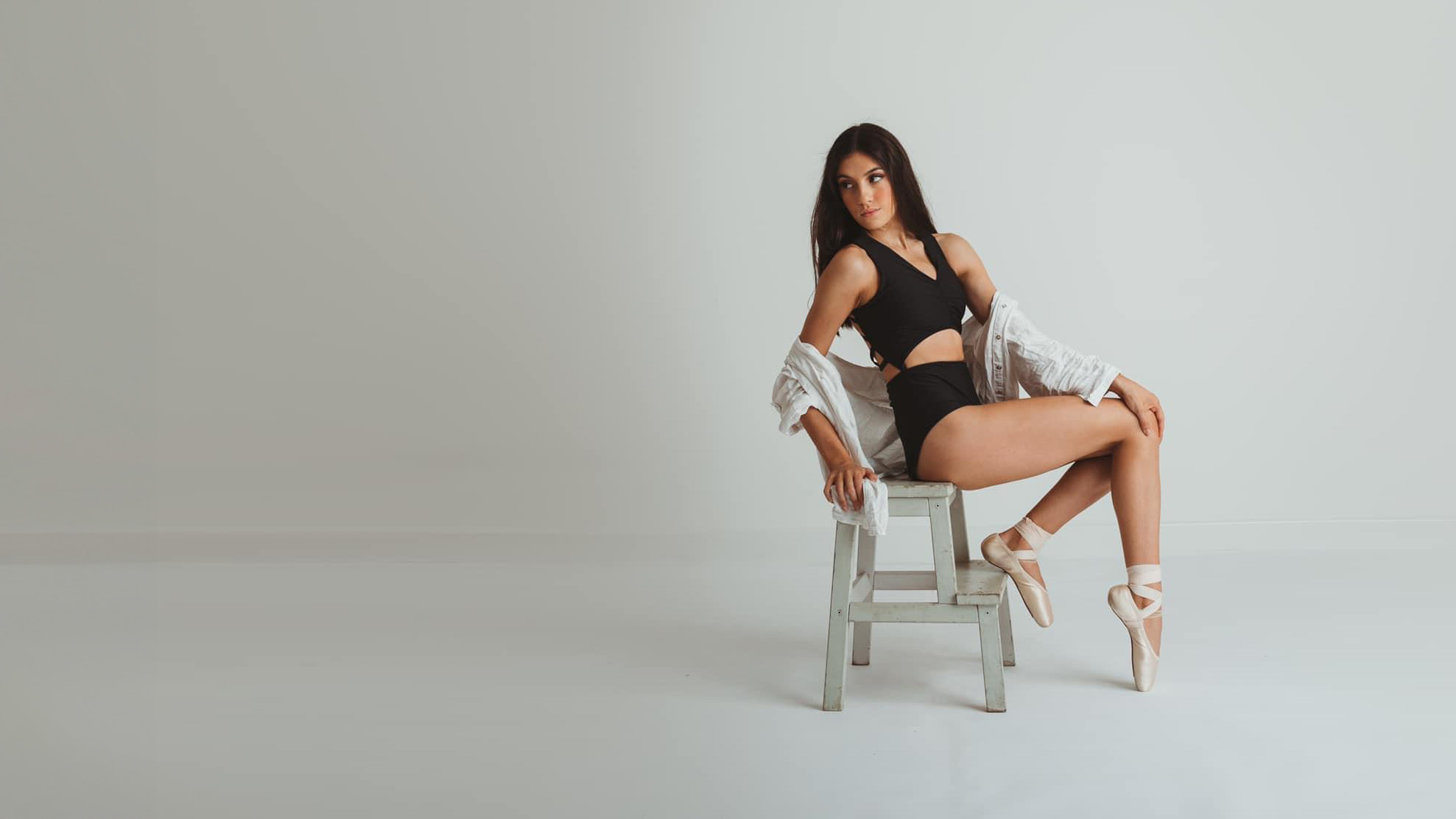 Teenager in ballet outfit sitting on chair gazing right